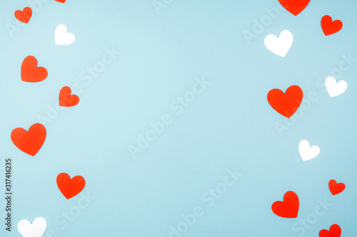 Minimalistic blue background for Valentine's day with paper hearts.