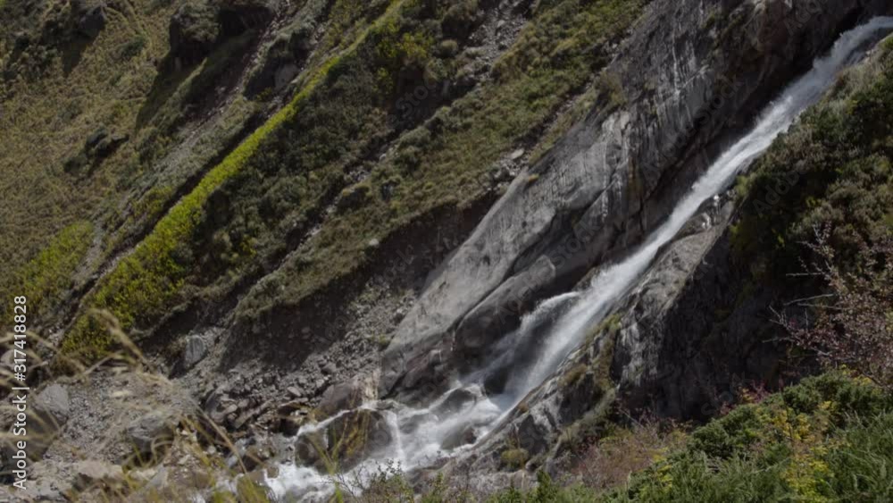 Natural Waterfall in Himalayas, Garhwal Himalayan range, near Kedarnath Temple in Uttarakhand, India.Falling water hitting water surface, some huge rocks see able in front of frame. Lush green leaf. Natural Waterfall in Himalayas, Garhwal Himalayan range, near Kedarnath Temple in Uttarakhand, India.Falling water hitting water surface, some huge rocks see able in front of frame. Lush green leaf.