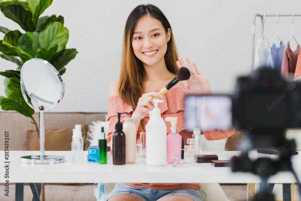 Beautiful asian woman blogger is showing how to make up and use cosmetics. In front of the camera and recording vlog video live streaming at home.Skincare for healthy face concept. Beautiful asian woman blogger is showing how to make up and use cosmetics. In front of the camera and recording vlog video live streaming at home.Skincare for healthy face concept.