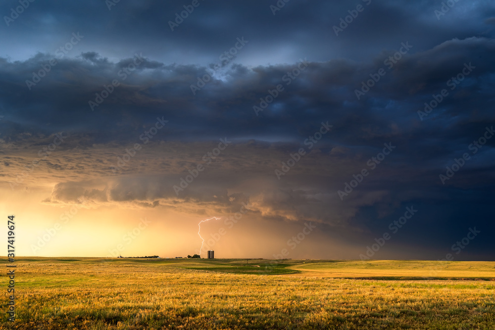 Stormy sky over a farm field at sunset - obrazy, fototapety, plakaty 