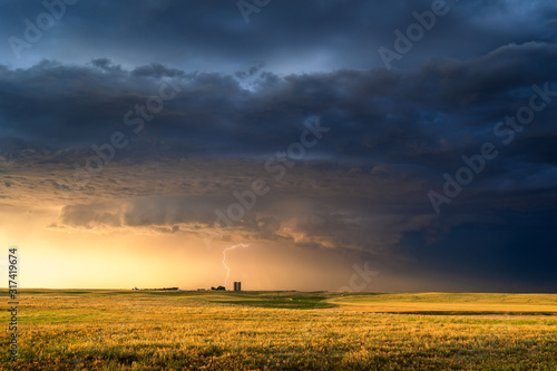 Fototapeta Naklejka Na Ścianę i Meble -  Stormy sky over a farm field at sunset