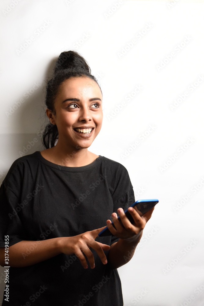 Beautiful middle eastern girl hold her phone chatting with a smile on a white background. Beautiful middle eastern girl hold her phone chatting with a smile on a white background.