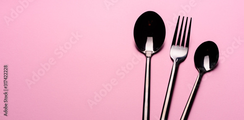 Metal Spoon and fork Isolated on pink background. Set of tableware ready for the meal