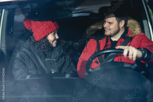 couple in car in winter outfit driving and talking navigation on phone © phpetrunina14