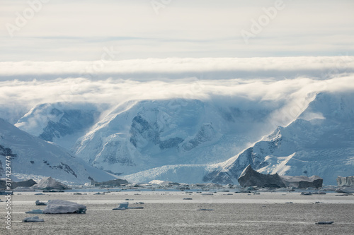 Snow and ice on the mountains near the water in Antarctica, a pristine remote environment affected by global warming and climate change