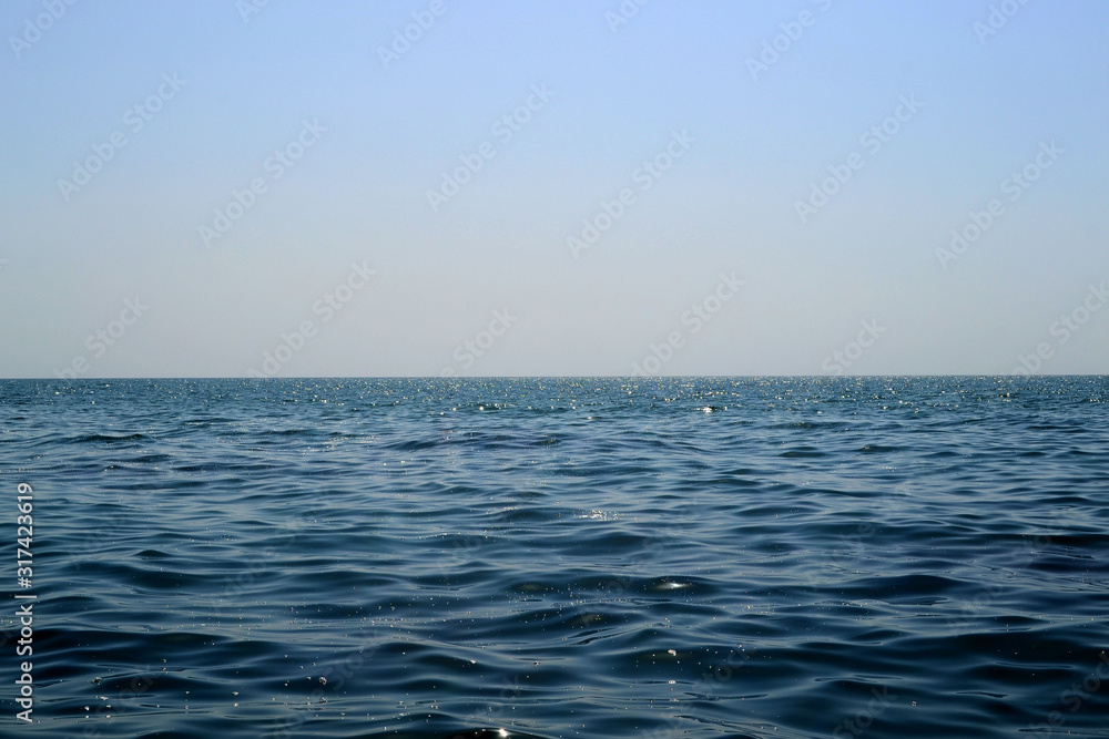 Fototapeta premium Nature background. Drops of water on the surface of the blue sea glow under the sun