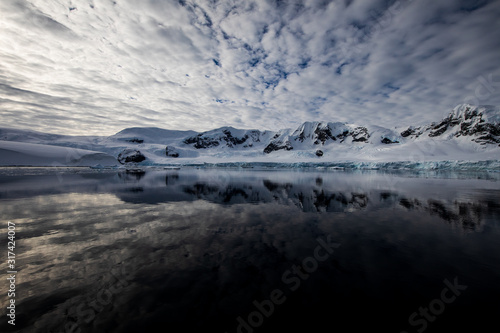 Snow and ice of the mountains reflected in the water in Antarctica  a pristine remote landscape
