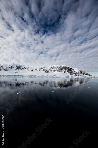 Fototapeta Naklejka Na Ścianę i Meble -  Snow and ice of the mountains reflected in the water in Antarctica, a pristine remote landscape