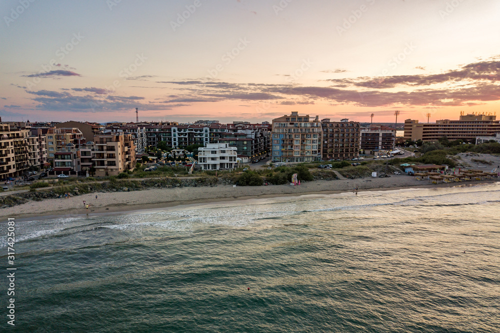 Obraz premium Aerial view of Pomorie city that is located on Black Sea shore. Top view of sand beaches with many hotel buildings and tourist infrastructure.