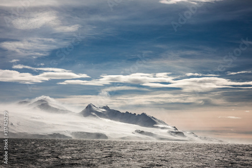 Snow and ice on the mountains near the water in Antarctica, a pristine remote landscape