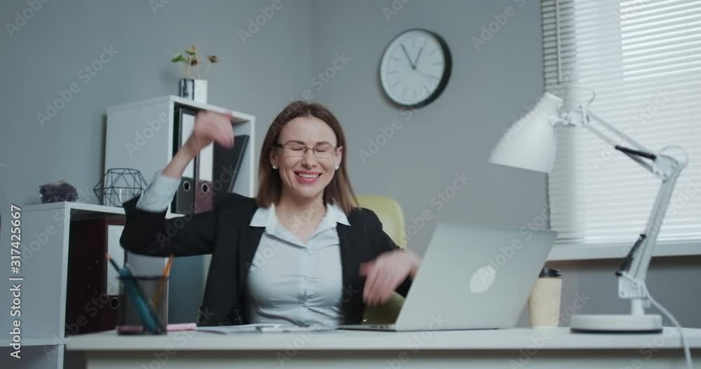 Portrait of the Beautiful Businesswoman Dancing While Sitting at Her Desk. Successful and Happy Woman Celebrating Record Sales. Portrait of the Beautiful Businesswoman Dancing While Sitting at Her Desk. Successful and Happy Woman Celebrating Record Sales.