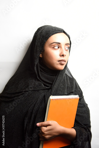 Muslim girl wearing Hijab, hugs orange book on a white background.