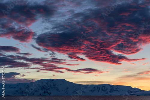 Pink clouds at sunset over the mountains and water of Antarctica, a pristine remote landscape