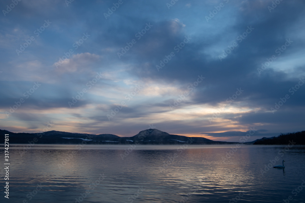早朝の屈斜路湖。雲の広がる夜明けの空と白鳥の湖。北海道