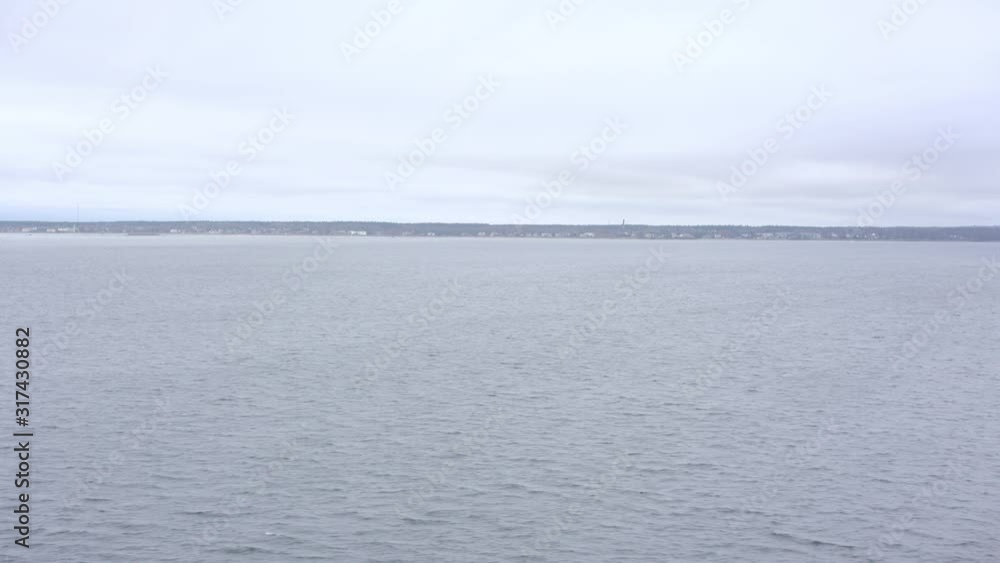 pictorial Helsinki coastline silhouette on horizon under cloudy sky and rippling grey sea water surface on foreground pictorial Helsinki coastline silhouette on horizon under cloudy sky and rippling grey sea water surface on foreground
