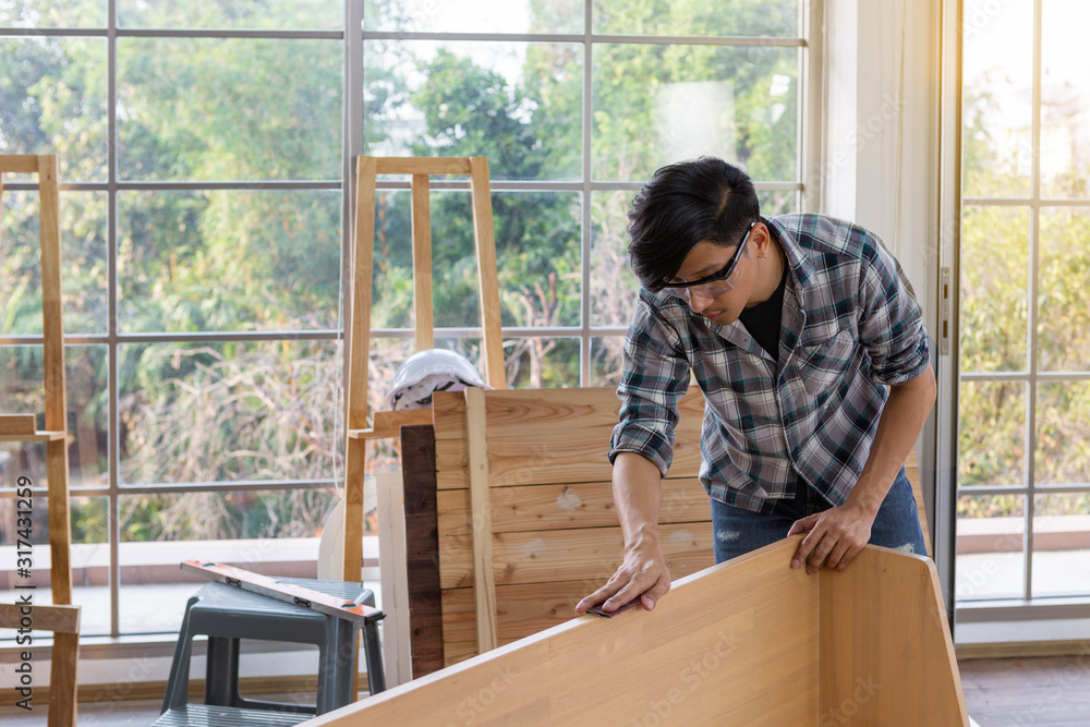 Young asian carpenter wearing safety glasses polishing wooden job with sandpaper - Handyman and diy concept Young asian carpenter wearing safety glasses polishing wooden job with sandpaper - Handyman and diy concept