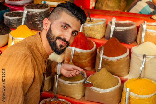 Canvas Print indian sallerman showing his small shop on arambol goa market
