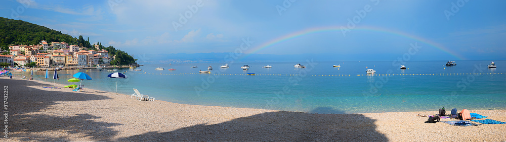 Fototapeta premium beach panorama Moscenicka Draga, adriatic ocean with boats, rainbow over the water