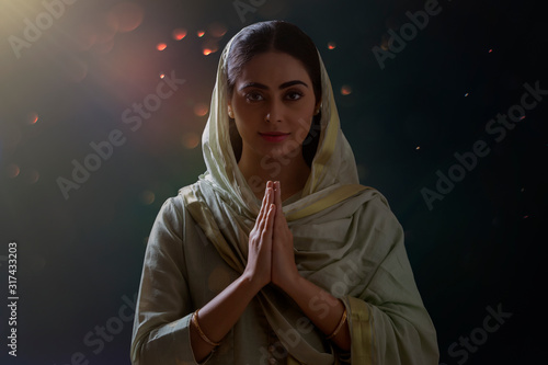 Portrait of a single woman praying with her hands folded. 