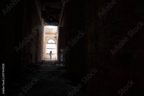 A man at the end of a dark corridor inside an abandoned building. An intimidating view inside a ghostly building