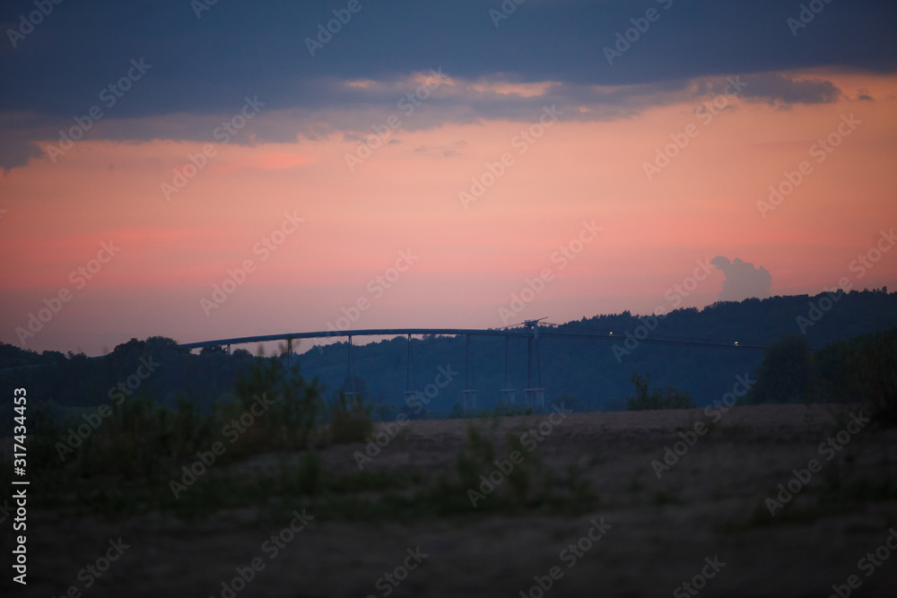 Overpass across the river against a pink sky. Bridge at sunset