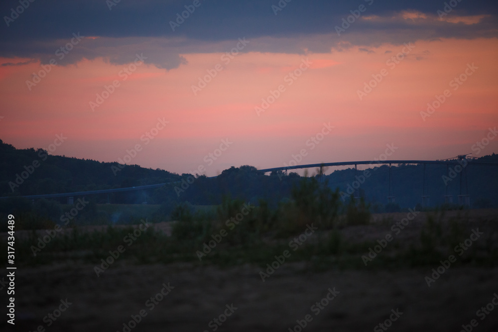 Overpass across the river against a pink sky. Bridge at sunset