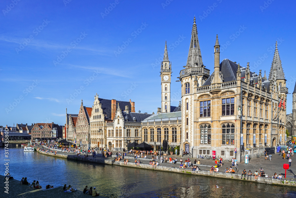 Tourists on quay along the river Lys / Leie and view over medieval guildhalls at the Graslei / Grass Lane in the city Ghent, East Flanders, Belgium