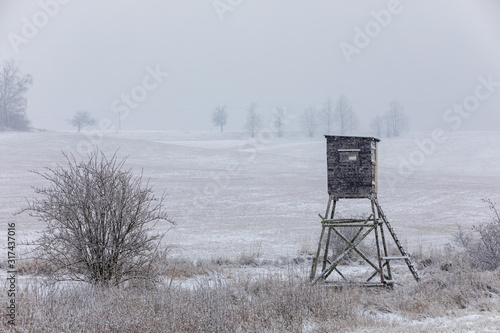 Winter european landscape with hunting tower covered with snow and heavy snowfall storm with falling snowflakes. Christmas concept.