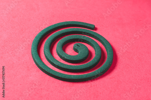 A green mosquito coil on a red background, side view photo