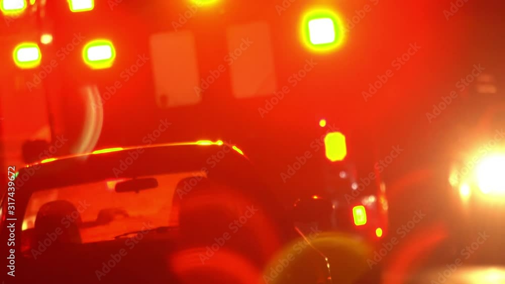 Cars driving past accident on side of the road at night with lights flashing from emergency vehicles. Cars driving past accident on side of the road at night with lights flashing from emergency vehicles.