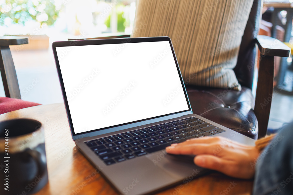 Mockup image of a woman using and touching on laptop touchpad with blank white desktop screen on the table Mockup image of a woman using and touching on laptop touchpad with blank white desktop screen on the table