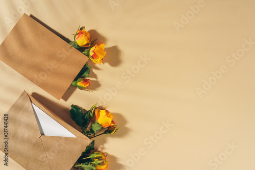 Craft paper envelope with yellow roses on beige background