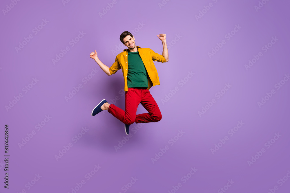 Full size photo of cheerful guy jump raise fists enjoy spring time discounts wear casual style outfit isolated over vibrant color background