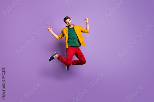 Full size photo of cheerful guy jump raise fists enjoy spring time discounts wear casual style outfit isolated over vibrant color background