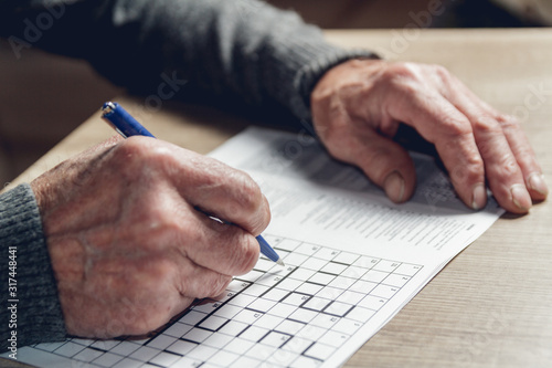 Senior solves sudoku or a crossword puzzle to slow the progressi photo