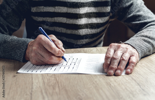 Senior solves sudoku or a crossword puzzle to slow the progressi photo