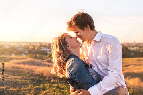 Happy young couple hugging and laughing outdoors. They are beautiful and full of love.
