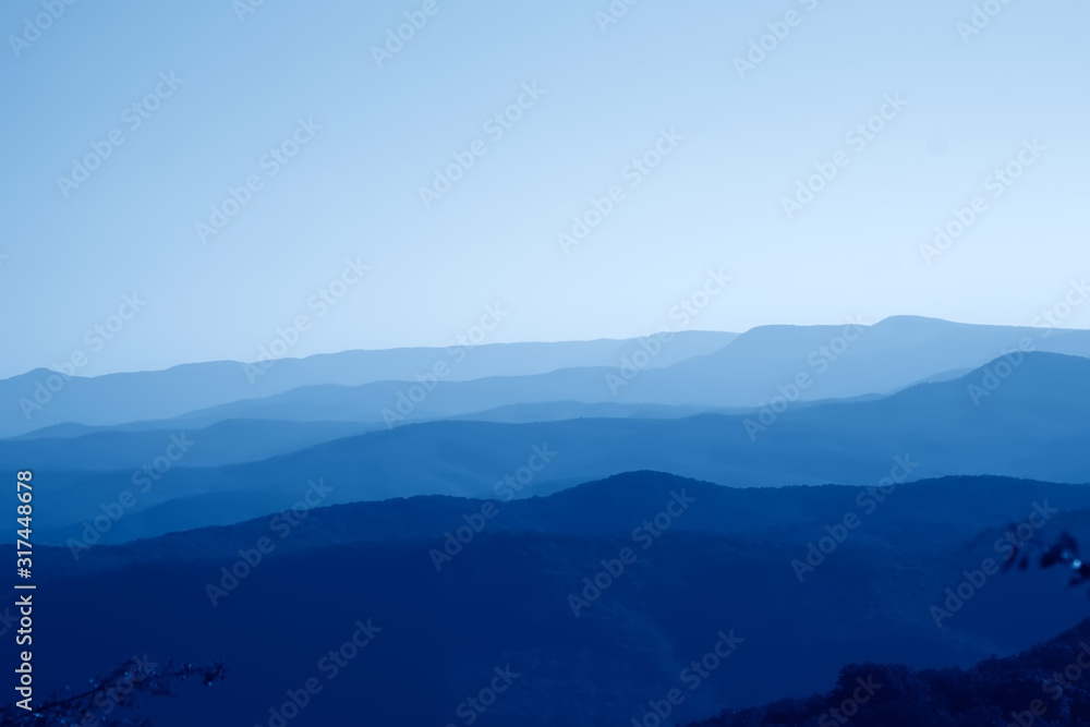 low mountains in haze. untouched mist nature away from man  toned in trendy Classic Blue color of the Year 2020