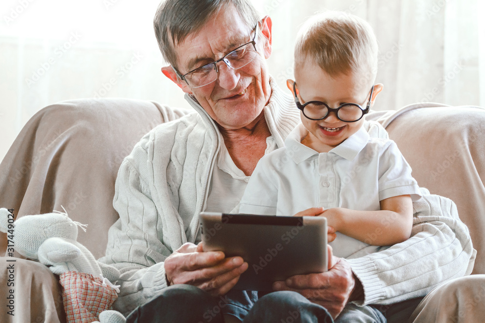 Elderly grandfather and his little grandson use a tablet device Elderly grandfather and his little grandson use a tablet device