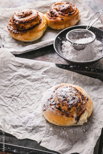 Vertical shot fresh sweet homemade cinnamon rolls with chocolate cream on a baking sheet. Scandinavian cuisine. Hyugge style photo