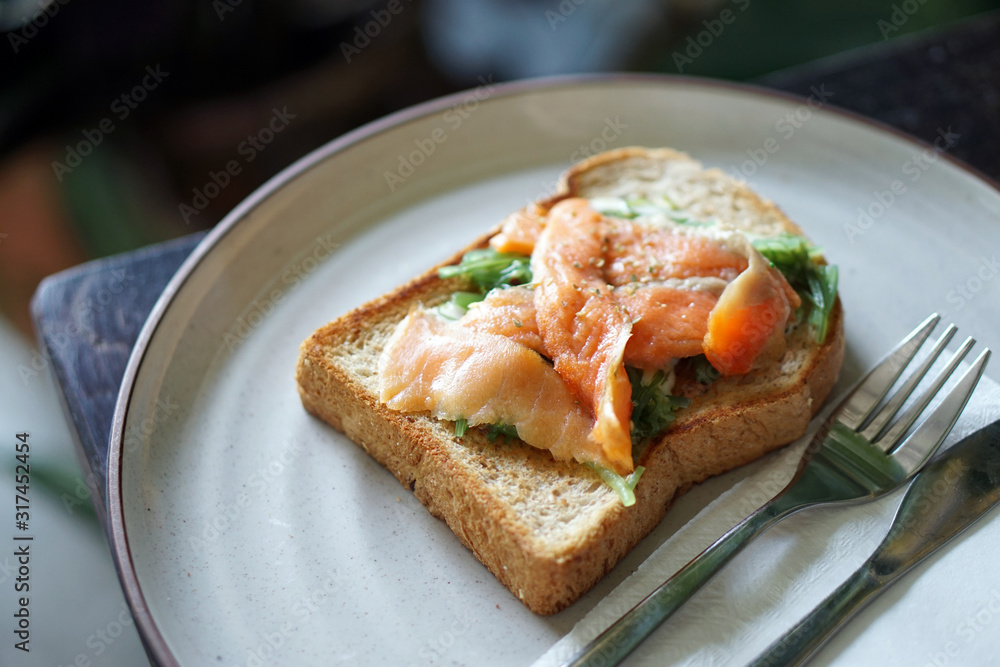 A plate of homemade smoked salmon and cream cheese toast served with japanese seaweed salad. A plate of homemade smoked salmon and cream cheese toast served with japanese seaweed salad.