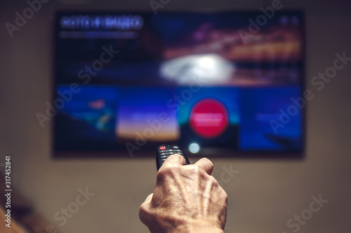 elderly man hand holding TV remote control.