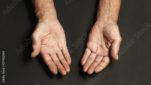 Wrinkled hands of an elderly man on a table close-up on a black