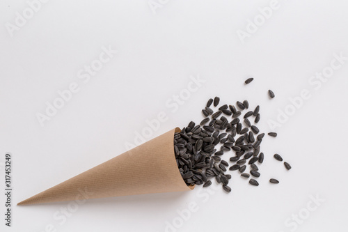 Fotografie Sunflower seeds in paper cone isolated on white background