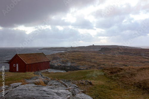 Old wooden boathouse in the rain by the sea in Norway