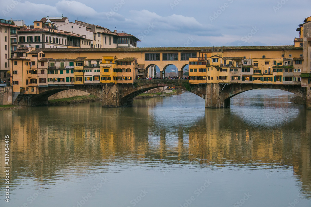 View of the historic Ponte Vecchio with gorgeous reflections in the Arno river during winter season, Florence, Tuscany, Italy