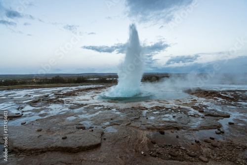 The famous geysir/Strokur with explosion, in Haukadalur valley near Reykjavik in Iceland during blue hour with no people around. Traveling and explorer concept.