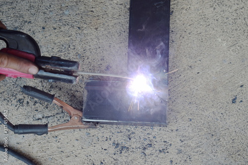 The mechanic is welding the black steel, creating a white spark.