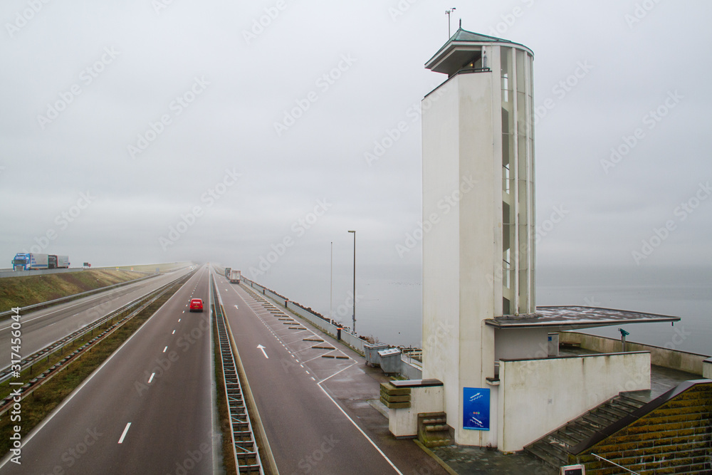 Traffic on the Afsluitdijk, a vast dike between the IJsselmeer en de Waddenzee in the Netherlands Traffic on the Afsluitdijk, a vast dike between the IJsselmeer en de Waddenzee in the Netherlands