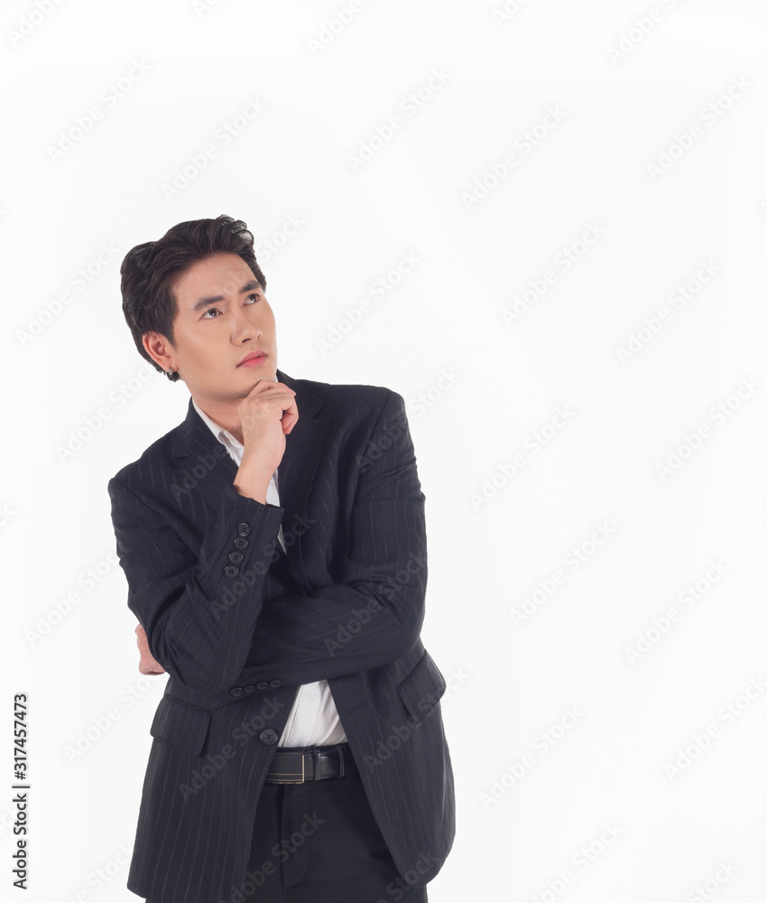 Portrait of an Asian business man wearing a black suit, standing with his arms crossed, hand on chin and looking up on a white background,isolated Portrait of an Asian business man wearing a black suit, standing with his arms crossed, hand on chin and looking up on a white background,isolated